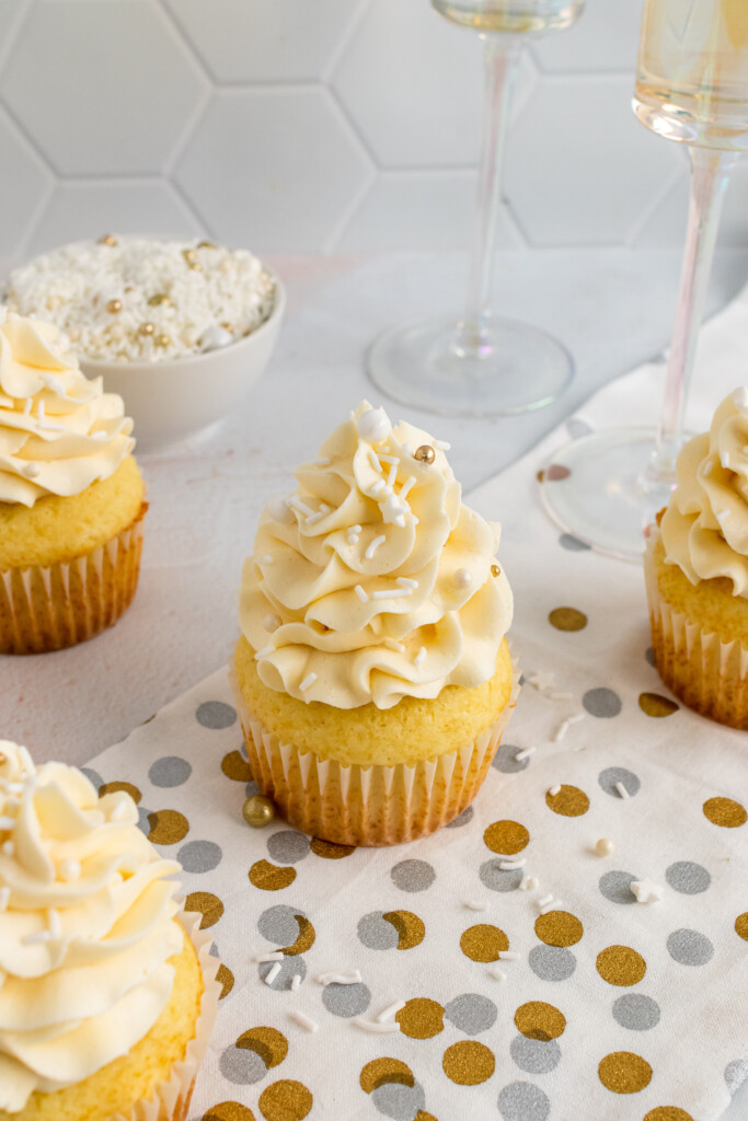 Champagne Cupcakes with sprinkles served with flutes of champagne.