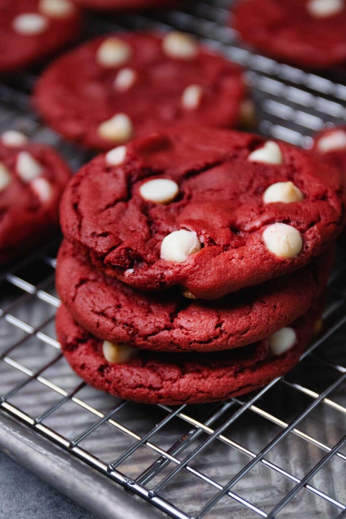 Red Velvet Cake Mix Cookies with white chocolate chips stacked on a cooking rack.