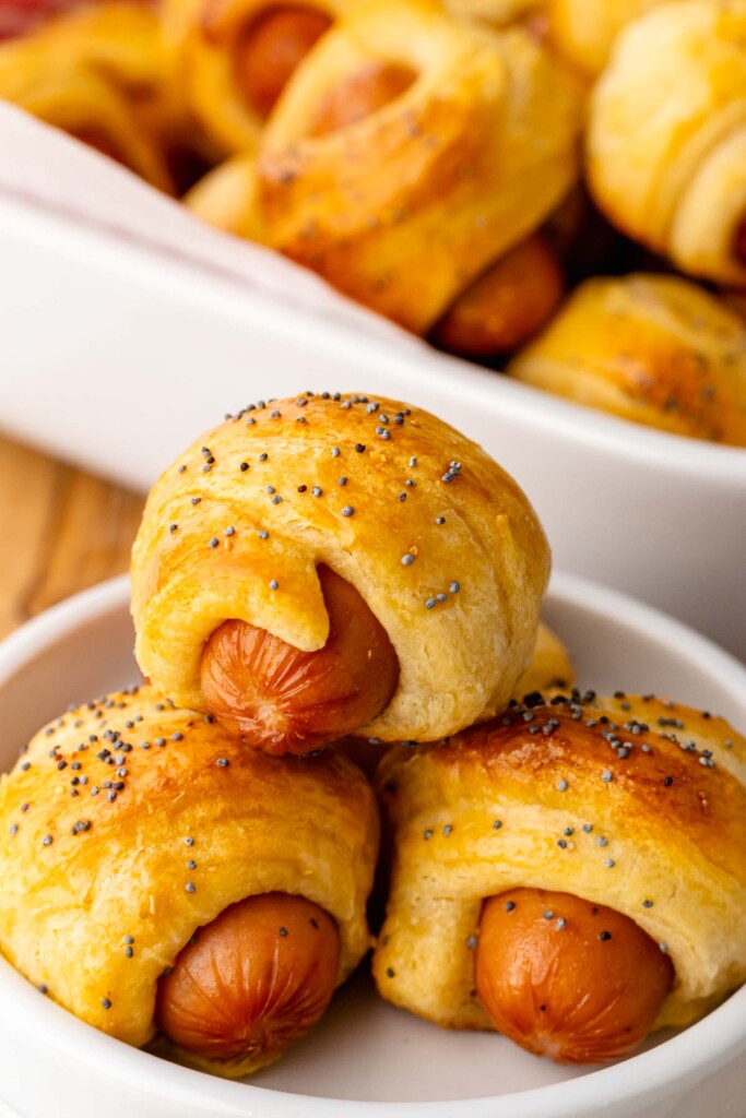 Pigs in a blanket on a white plate for snacks.