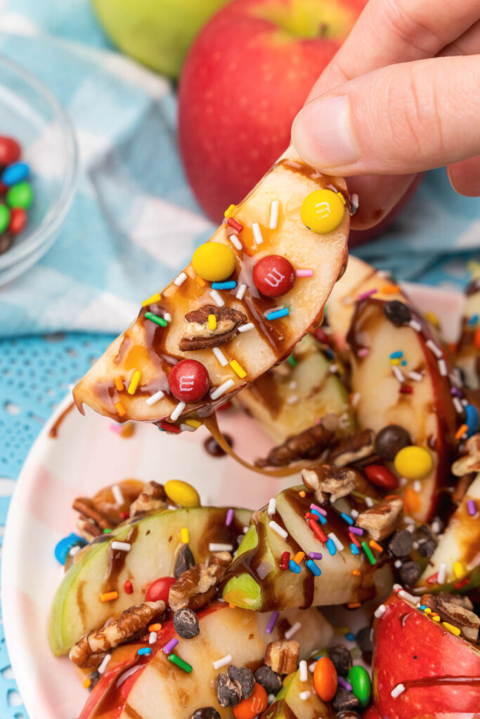 Apple Nachos drizzled with caramel, chocolate, sprinkles and topped with chocolate chips, M&M's and pecans is a treat that young and old loves! The perfect way to celebrate lifes little joys.